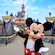 Mickey Mouse with arms outstretched in front of Sleeping Beauty Castle