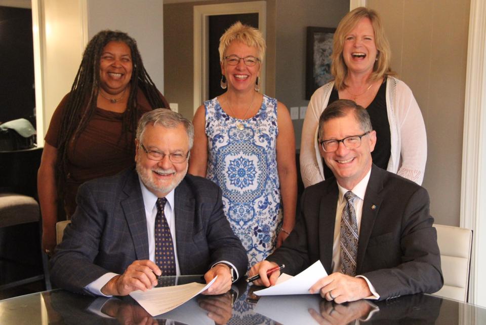 Peter Morales (L) and John Dorhauer, presidents, respectively, of the UUA and the United Church of Christ, backed by staff of both organizations, sign a Memorandum of Understanding to continue partnering on Our Whole Lives sexuality education.