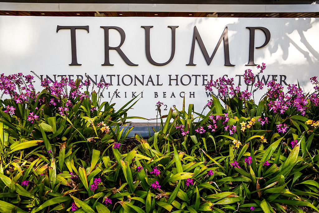 Tropical flowers and front entrance sign of Trump International Hotel Waikiki Beach. Five Star luxury hotel &amp; residences owned by Donald Trump