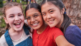 Three girls smiling, including Hannah who is transgender