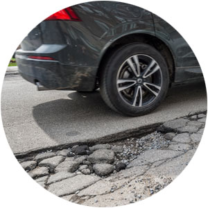 Car driving by a pothole on the street